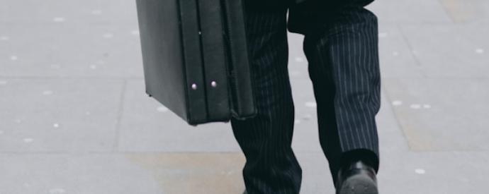 Person in a suit carrying a briefcase