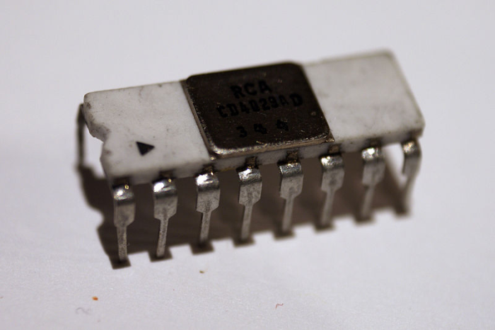 An old integrated circuit, closed, hundreds of transistors are hidden inside this package, a white oblong, with many copper legs