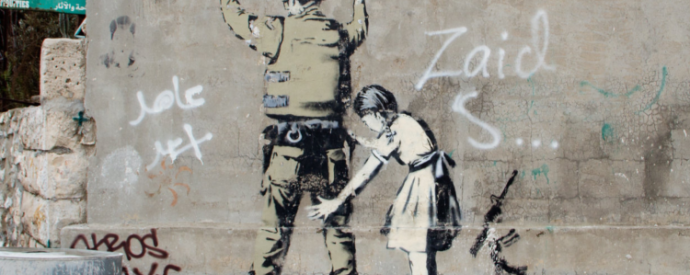 Banksy graffiti on the west Wall of Bethlehem, of a child frisking an armed soldier