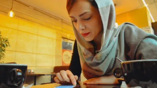 A person at a table in a cafe looking at a phone