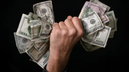 A wad of money being grabbed in a hand